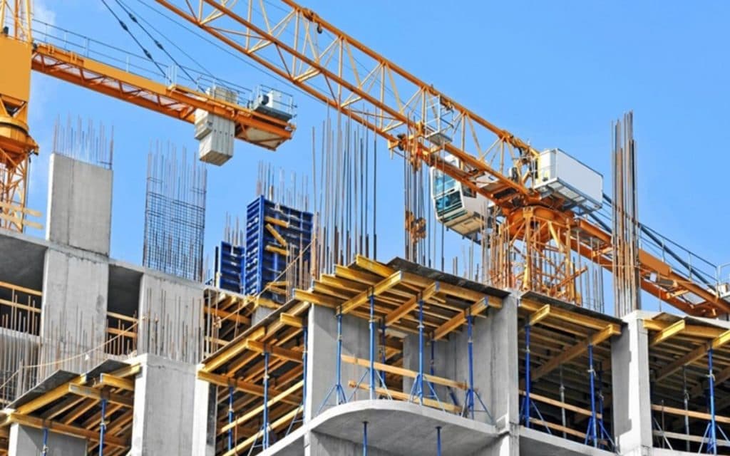 Obra en construcción con grúas y maquinaria amarilla